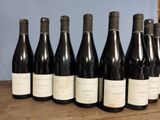 six bottles of wine are lined up on a wooden table