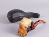 une pipe sur laquelle est représenté un visage d'homme, à côté d'un porte-pipe
