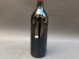 a bottle of wine sitting on top of a table next to a gray wall