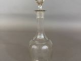 a clear glass bottle with a silver stopper sitting on top of a table