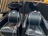 pair of black leather chairs with white trims in a salon