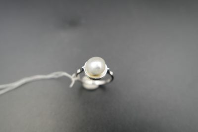 bague en argent ornée d'une perle blanche sur un fond noir