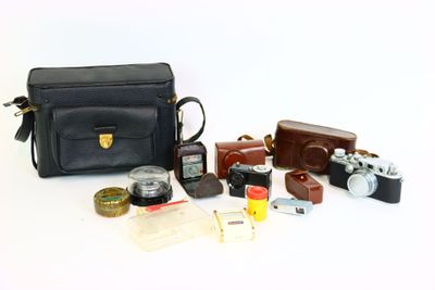 un sac noir sur lequel se trouvent un appareil photo, un étui pour appareil photo, un appareil photo et d'autres objets