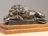 statue en bronze représentant un lion posé sur un socle posé sur une table