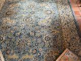 un tapis posé sur le sol d'un salon où se trouvent un fauteuil et une table