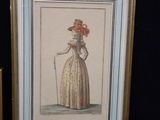 framed picture of a lady in a dress with a cane and a hat