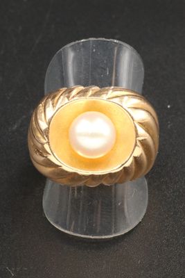 bague en perles jaunes et blanches posée sur un socle en acrylique transparent