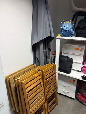 une petite pièce avec une étagère, une chaise, une valise et plusieurs autres objets