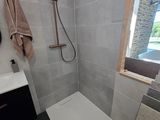 une salle de bains équipée d'une douche, d'un lavabo et d'un miroir