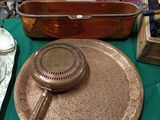 a large copper pan on a table with a teapot on it