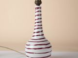 a red and white striped lamp on a white table