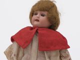 a small doll with a red scarf on it ' s head