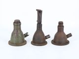 trois vieilles cloches en métal posées les unes à côté des autres sur une surface blanche