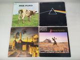 quatre pochettes d'albums de Pink Floyd posées sur une table, avec une vache en arrière-plan
