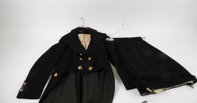 an image of a black suit with gold buttons and a pair of shoes