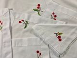 four white napkins with red cherries and green leaves on them