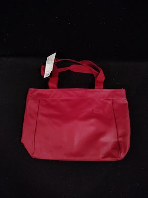 a red purse with a tag on it sitting on a black surface