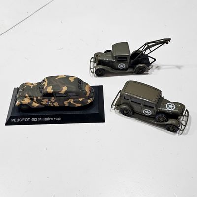 three toy army vehicles on display on a white surface