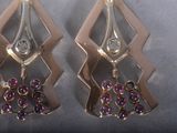 two pairs of earrings with purple stones on a silver surface
