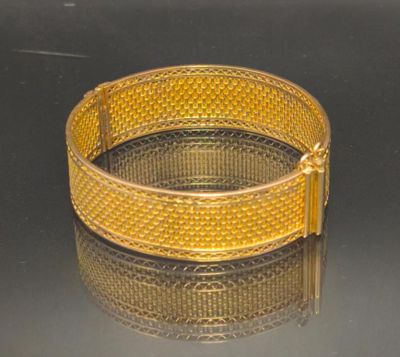 gold plated bracelet on a reflective surface with a black background