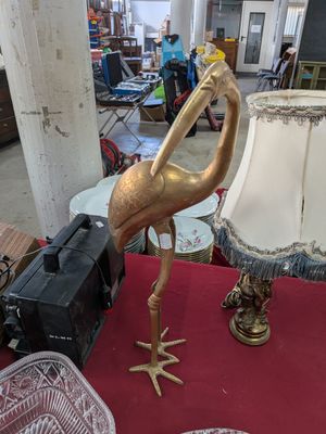 une statue de flamant rose en or posée sur une table rouge sur laquelle se trouve une lampe
