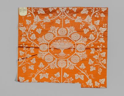 an orange and white floral design on a piece of fabric