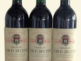 trois bouteilles de vin rouge posées l'une à côté de l'autre sur une surface blanche