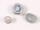 three pieces of silver and blue glass on a white surface