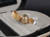 une montre en or posée dans un écrin sur une surface blanche