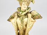 statue d'une femme vêtue d'une robe verte et coiffée d'un chapeau