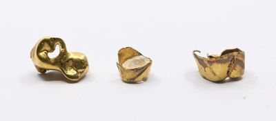three pieces of gold colored metal on a white surface