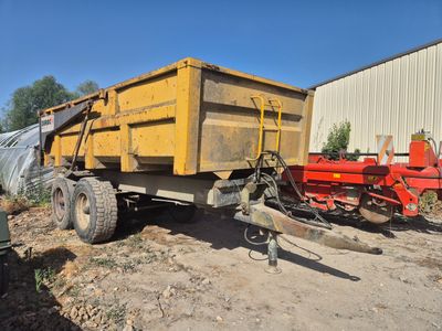 un camion-benne jaune garé à côté d'un tracteur rouge