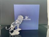 figurine en cristal représentant un lion posé sur une table, avec une boîte en arrière-plan