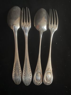 trois cuillères en argent et deux fourchettes en argent posées sur un fond noir
