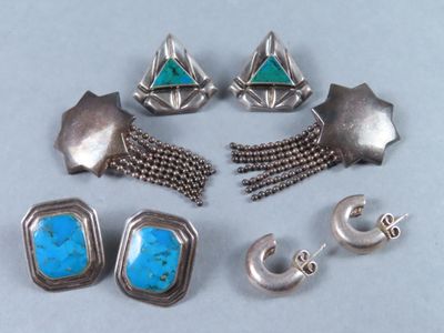 plusieurs bijoux en argent et en turquoise posés sur une table