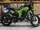 une moto verte et noire garée dans un entrepôt