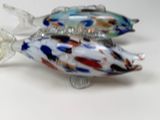 two glass fish figurines sitting on a white surface