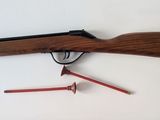 a close up of a rifle on a wall with a red arrow pointing to it