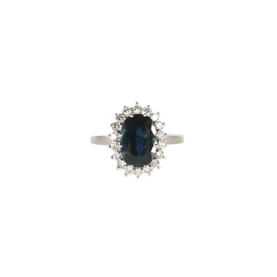 gros plan d'une bague avec une pierre bleue entourée de diamants blancs