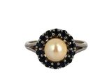 un gros plan d'une bague ornée d'une perle et d'un diamant noir sur fond blanc