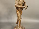 bronze statue of a boy holding a bird on a marble base