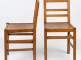 pair of wooden chairs against a white background with a white backdrop