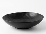 un bol noir posé sur une surface blanche