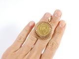 a woman ' s hand holding a ring with a gold coin on it