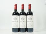 Trois bouteilles de vin rouge sont alignées sur une table blanche
