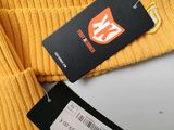 the yellow sweater is next to a tag on a white table