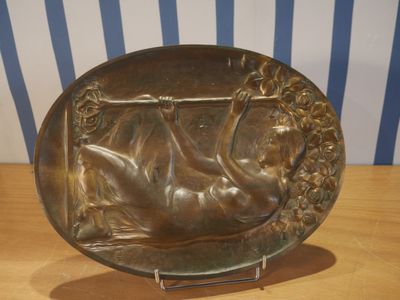 une plaque en bronze représentant une femme allongée sur un lit