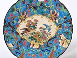 an image of a blue plate with a bird and flowers on it