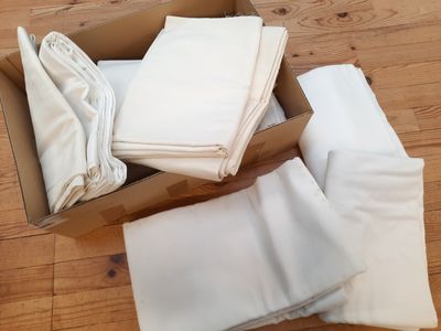 une boîte remplie de draps blancs pliés, posée sur un plancher en bois
