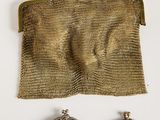 two small metal purses and a pair of earrings on a white surface